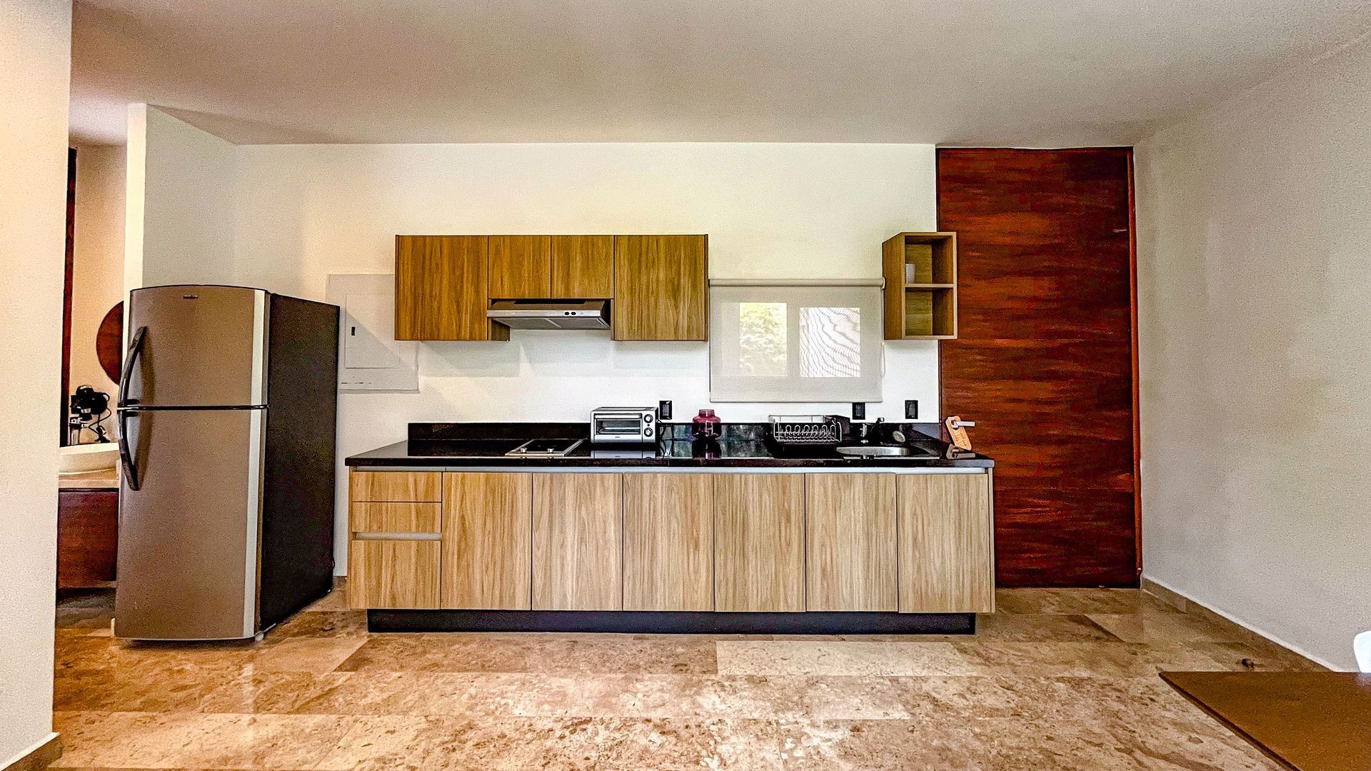 Cocina con gabinetes de madera y electrodomésticos de acero inoxidable contra una pared de color claro.
