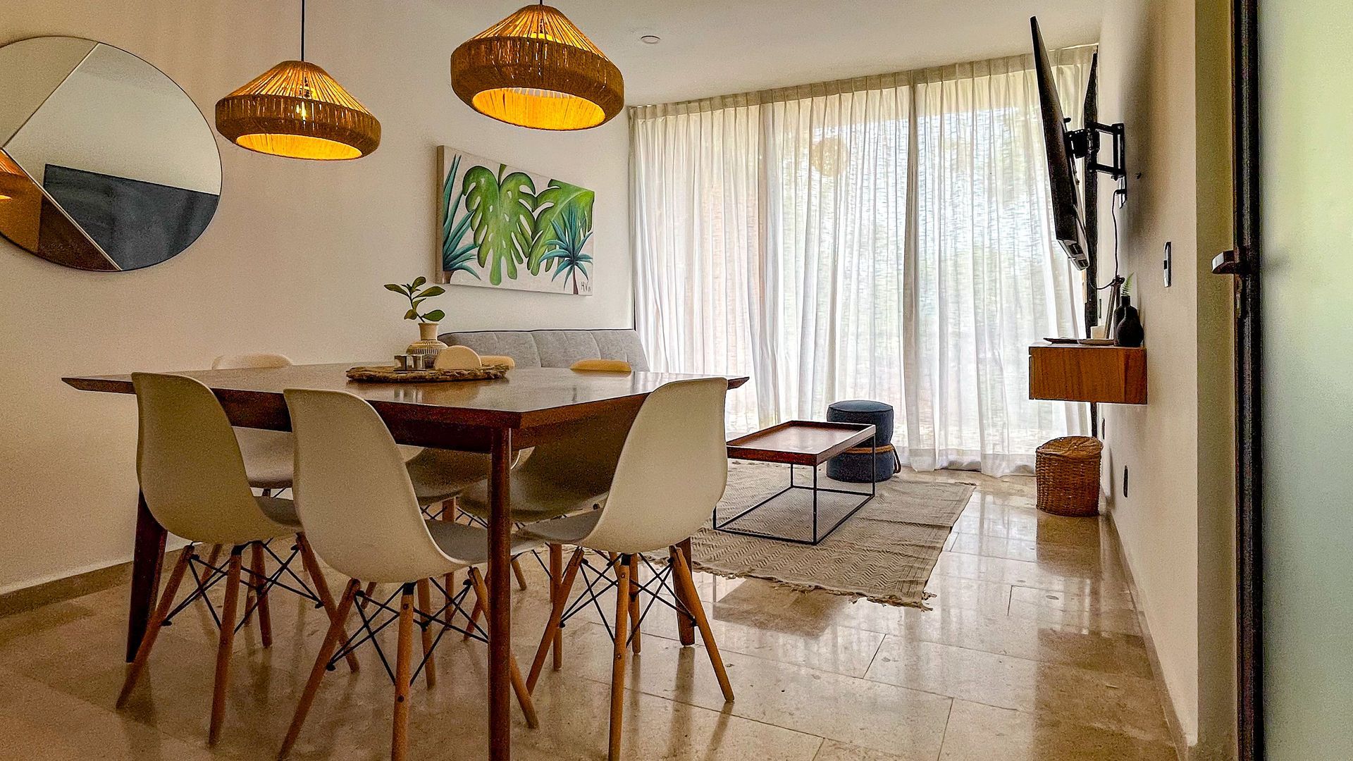 Comedor con mesa, sillas, arte, lámparas y gran ventanal.