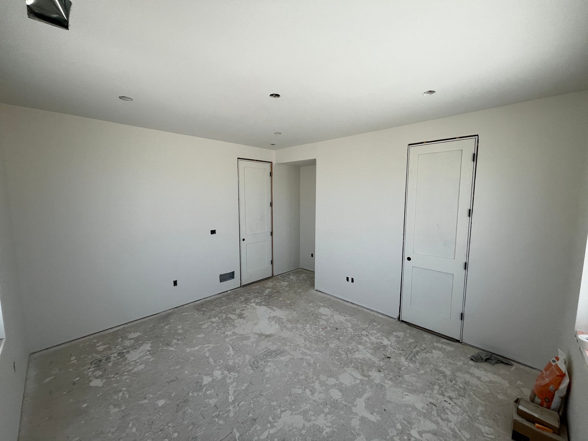 An empty room with white walls and a concrete floor