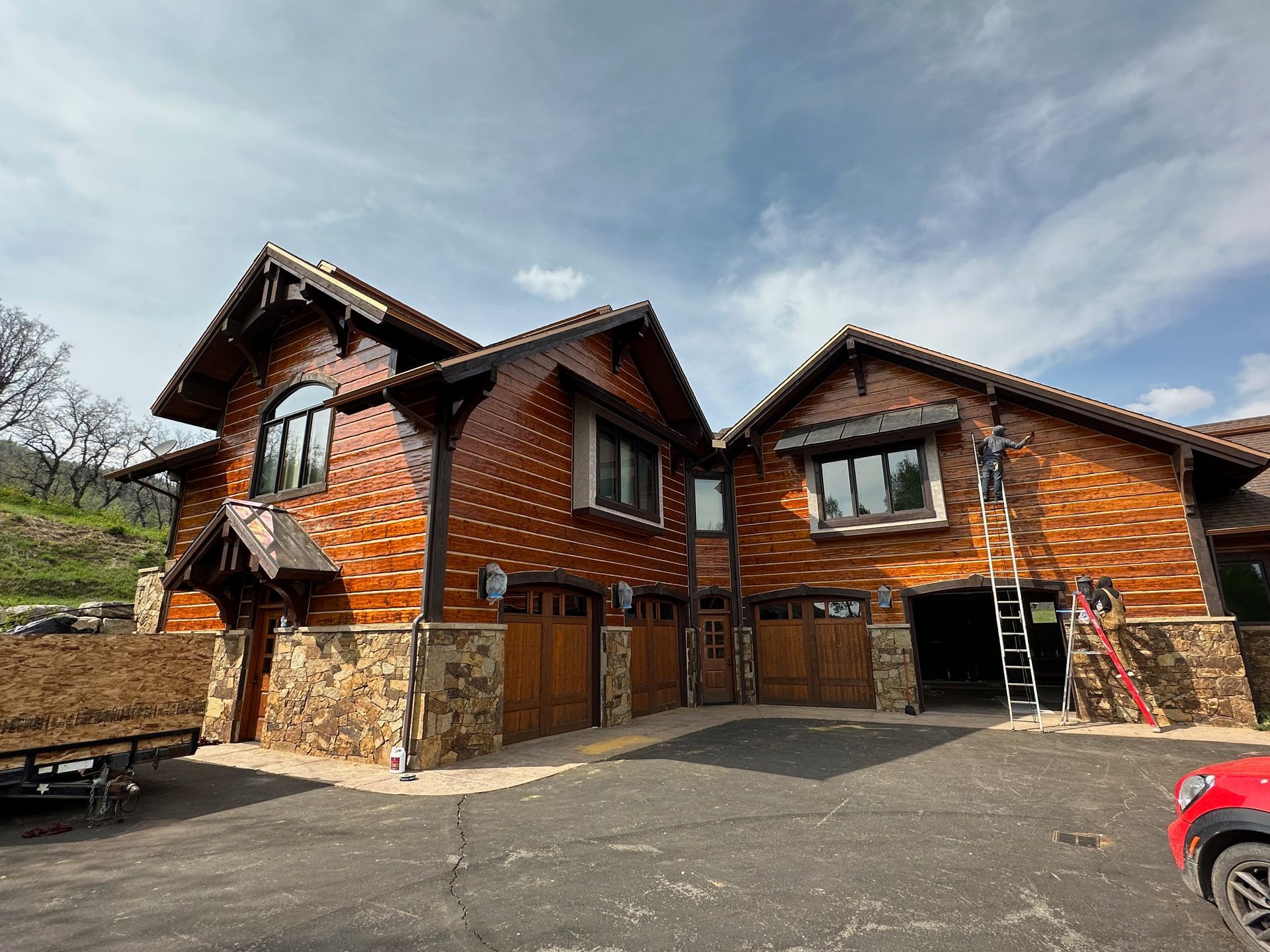 A large wooden house with two garage doors is being painted.