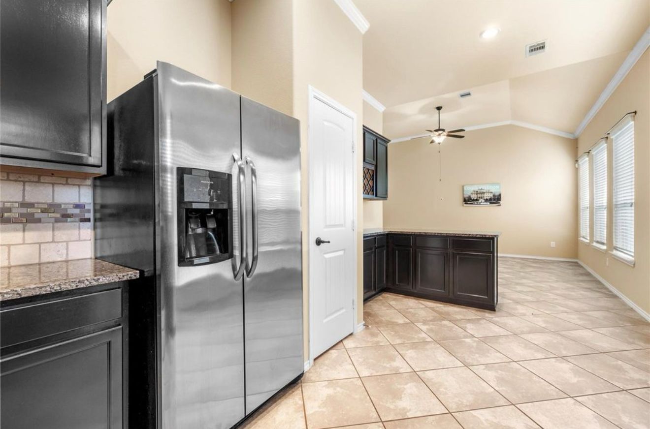 A kitchen with a stainless steel refrigerator and black cabinets.