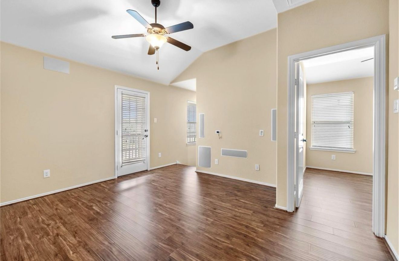 An empty living room with hardwood floors and a ceiling fan.