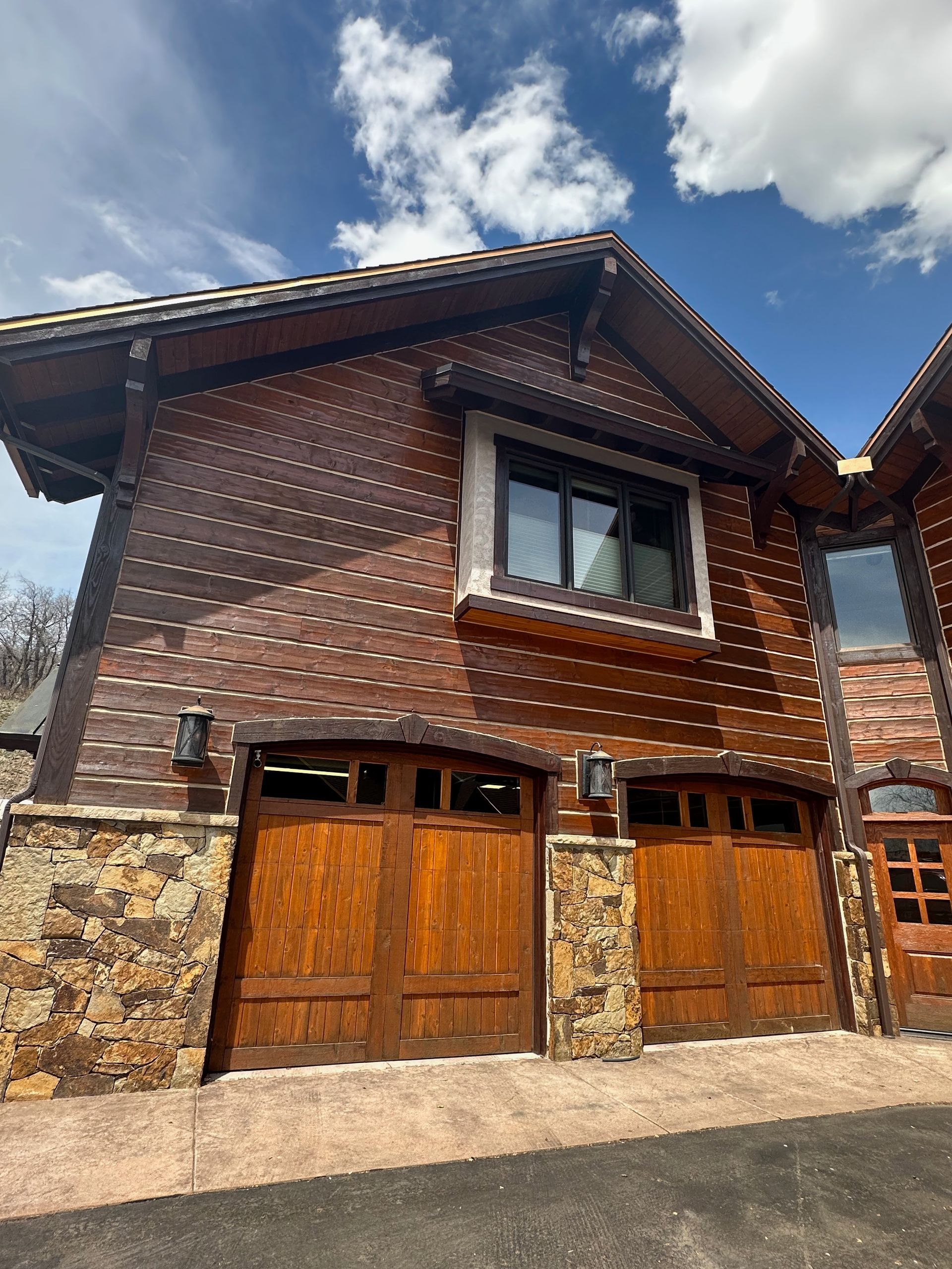 A wooden house with two wooden garage doors and a window