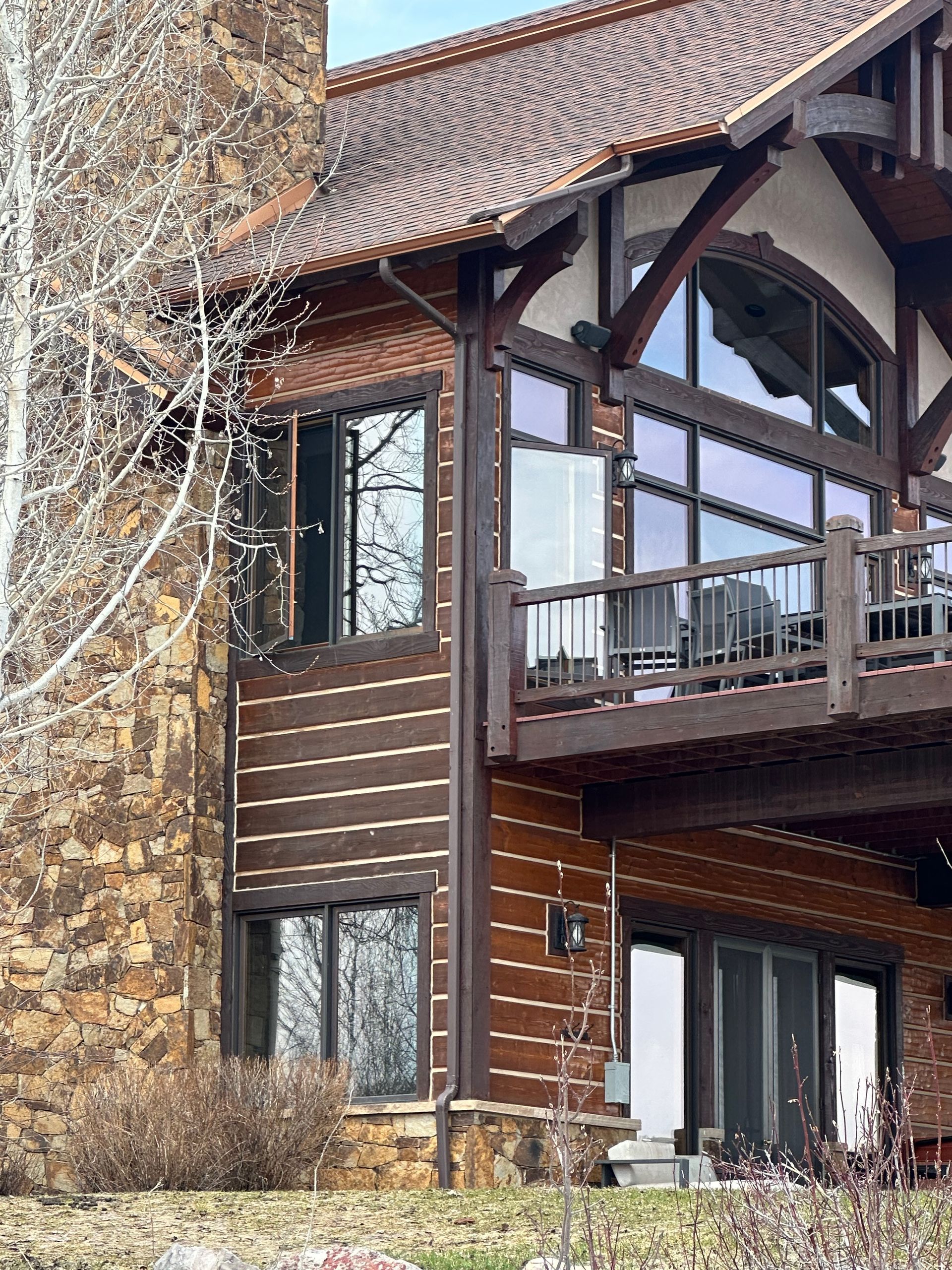 A large log cabin with a large deck and lots of windows.