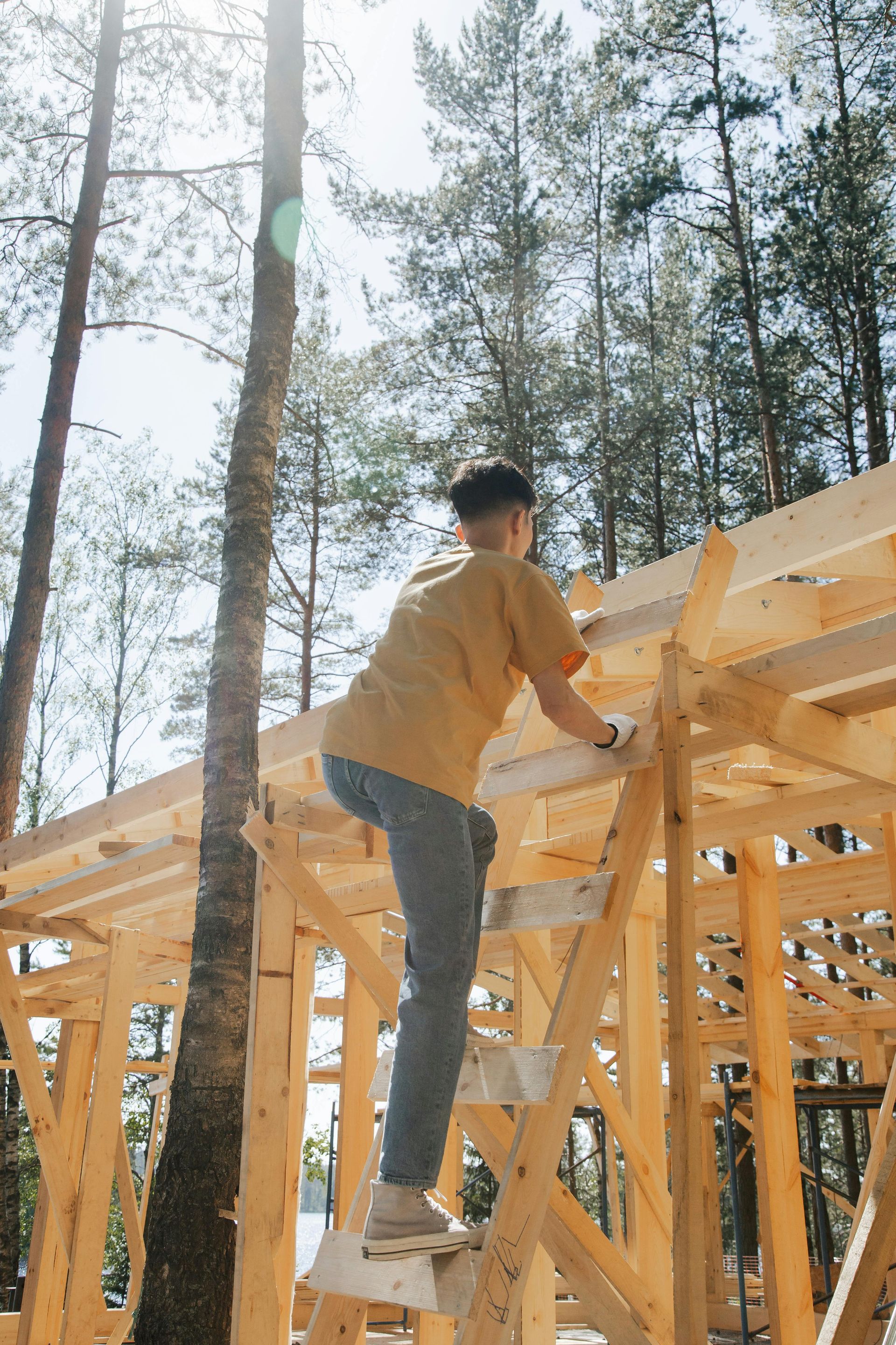 A man is climbing a wooden ladder to work on a wooden structure.