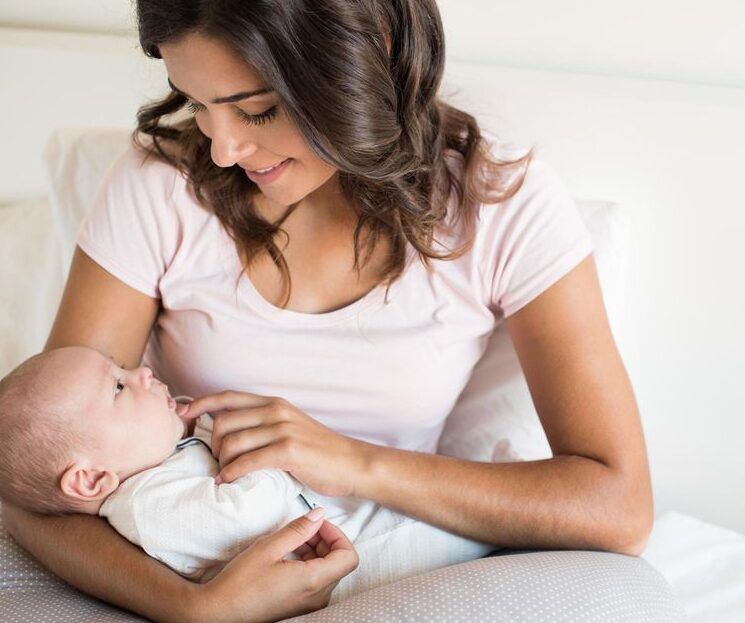 Woman in a white shirt holding and gazing at a baby on a couch
