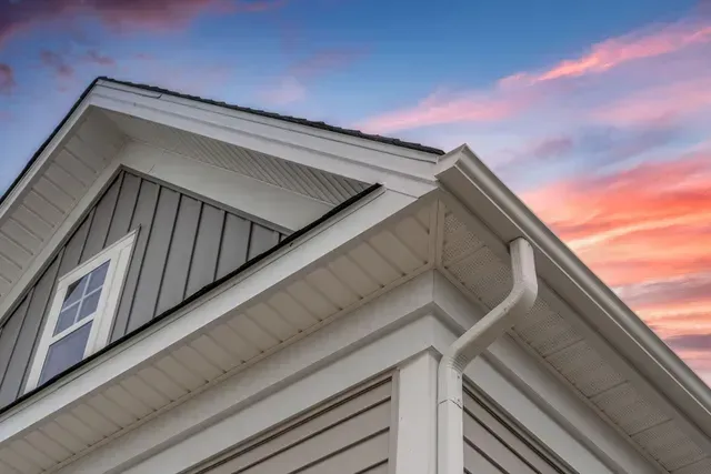 White gutter guard system on pitched roof, showcasing siding services, vinyl siding and soffit. White gutter guard system on pitched roof, showcasing siding services, vinyl siding and soffit.