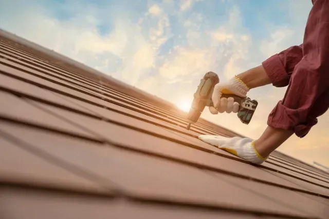 Man on roof at sunset, showcasing a roofing contractor’s skilled work and beautiful scenery. Man on roof at sunset, showcasing a roofing contractor’s skilled work and beautiful scenery.