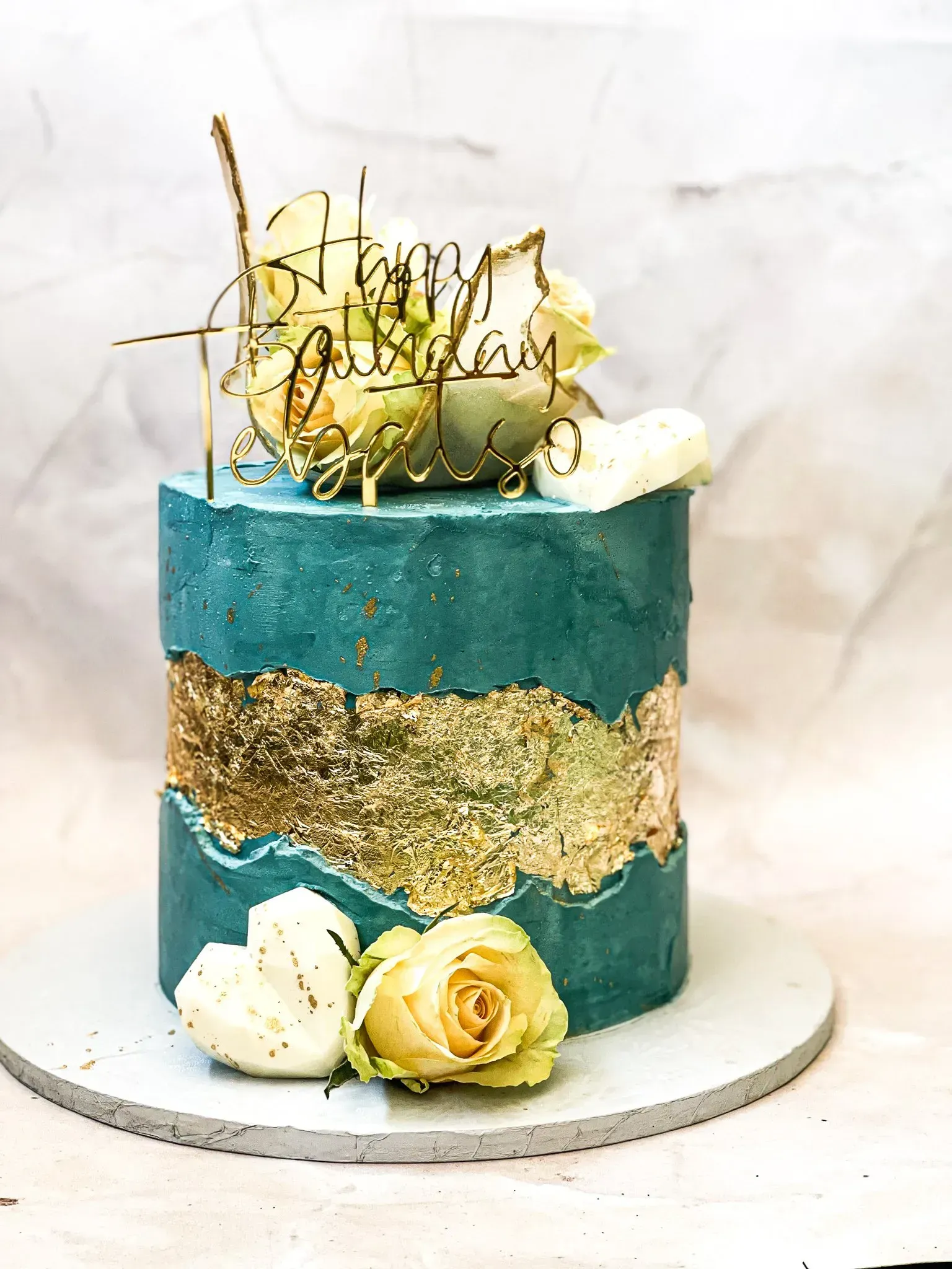 Teal and gold birthday cake with flowers and a 
