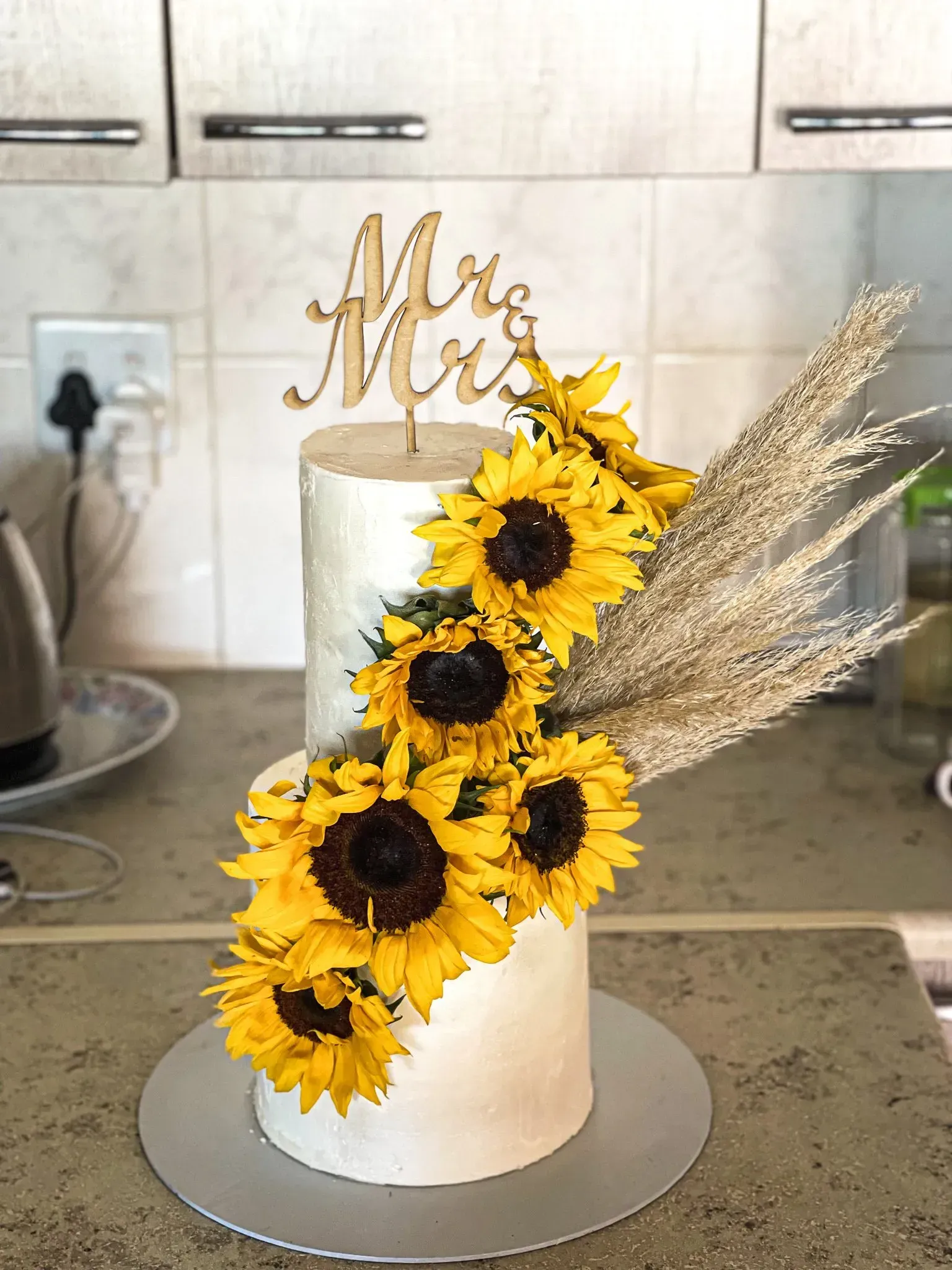 Two-tiered white frosted cake, decorated with sunflowers and wheat, 