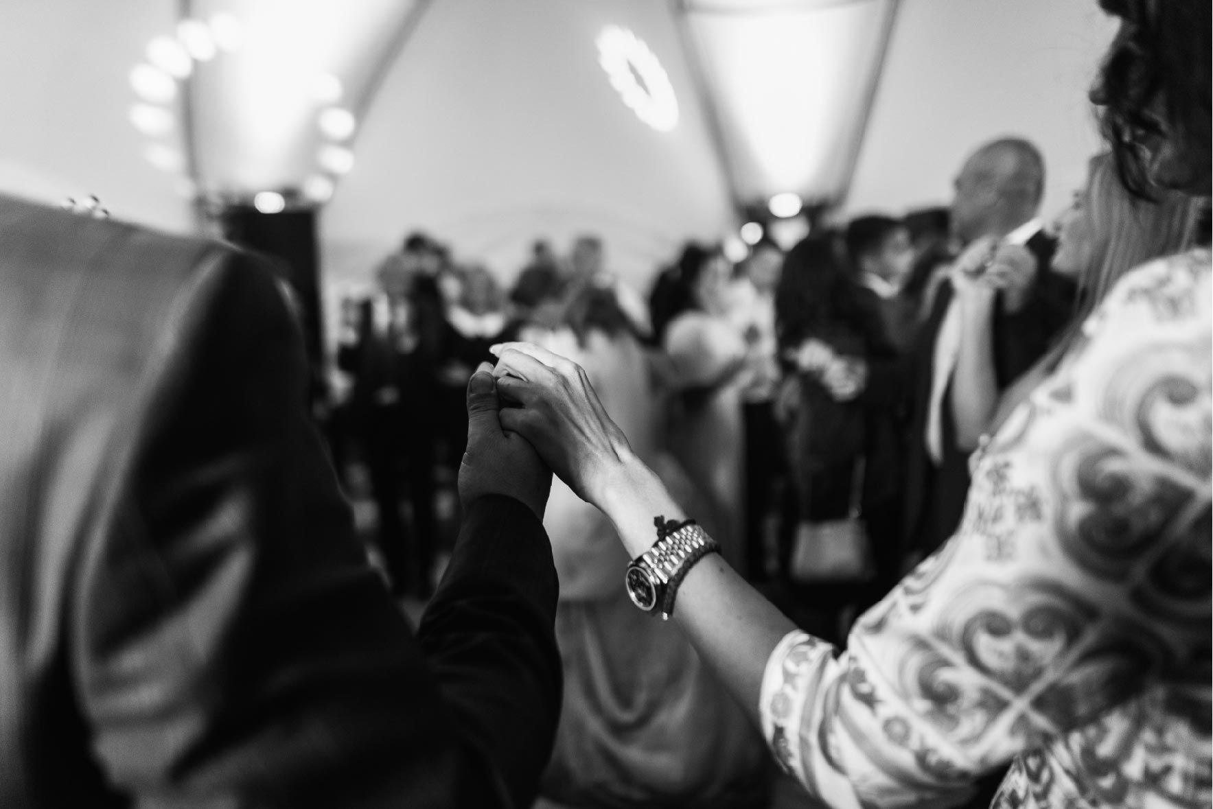 People dancing at a celebration, holding hands. Black and white photo.