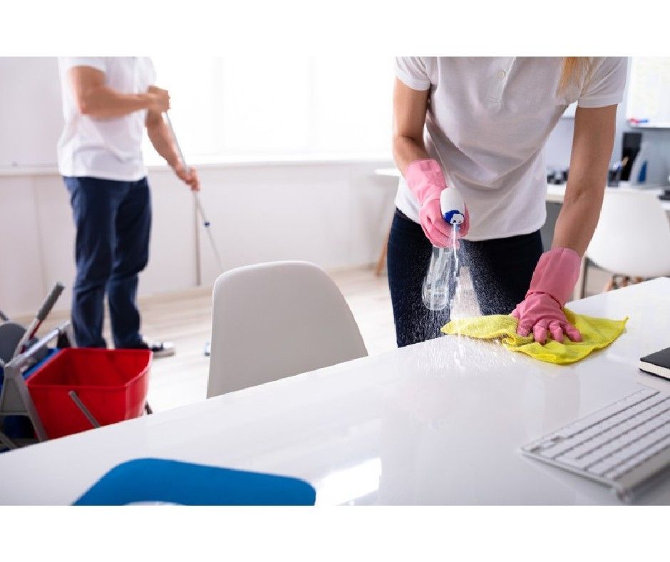 A man and a woman are cleaning a desk in an office.