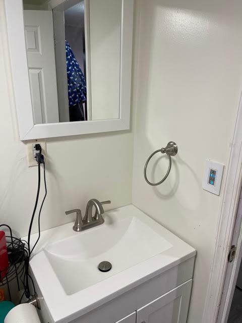 A bathroom with a sink , mirror and towel rack.