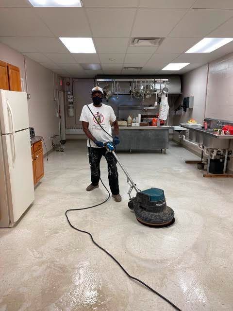 A man is cleaning the floor of a kitchen with a machine.