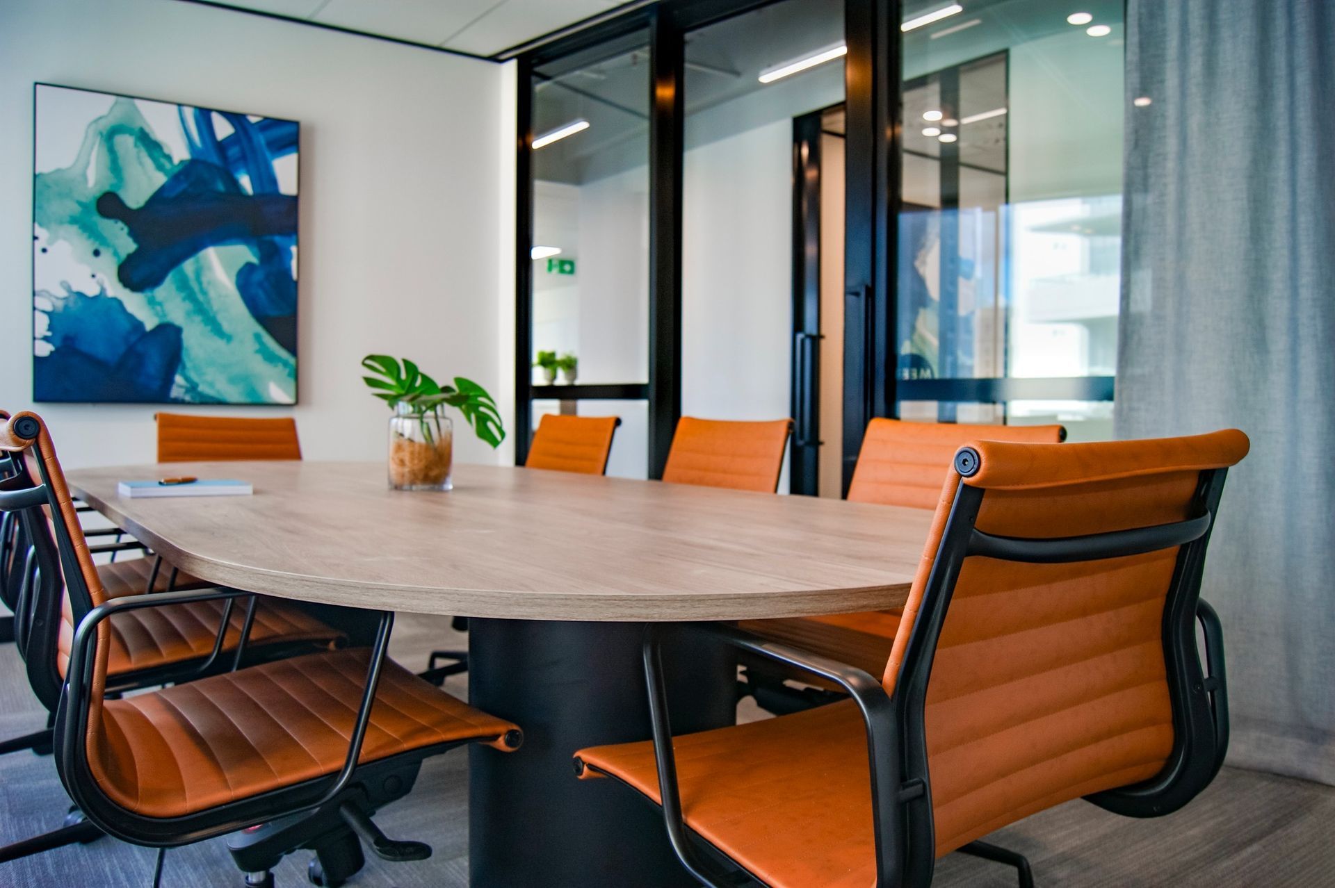 A conference room with a table and chairs and a painting on the wall.