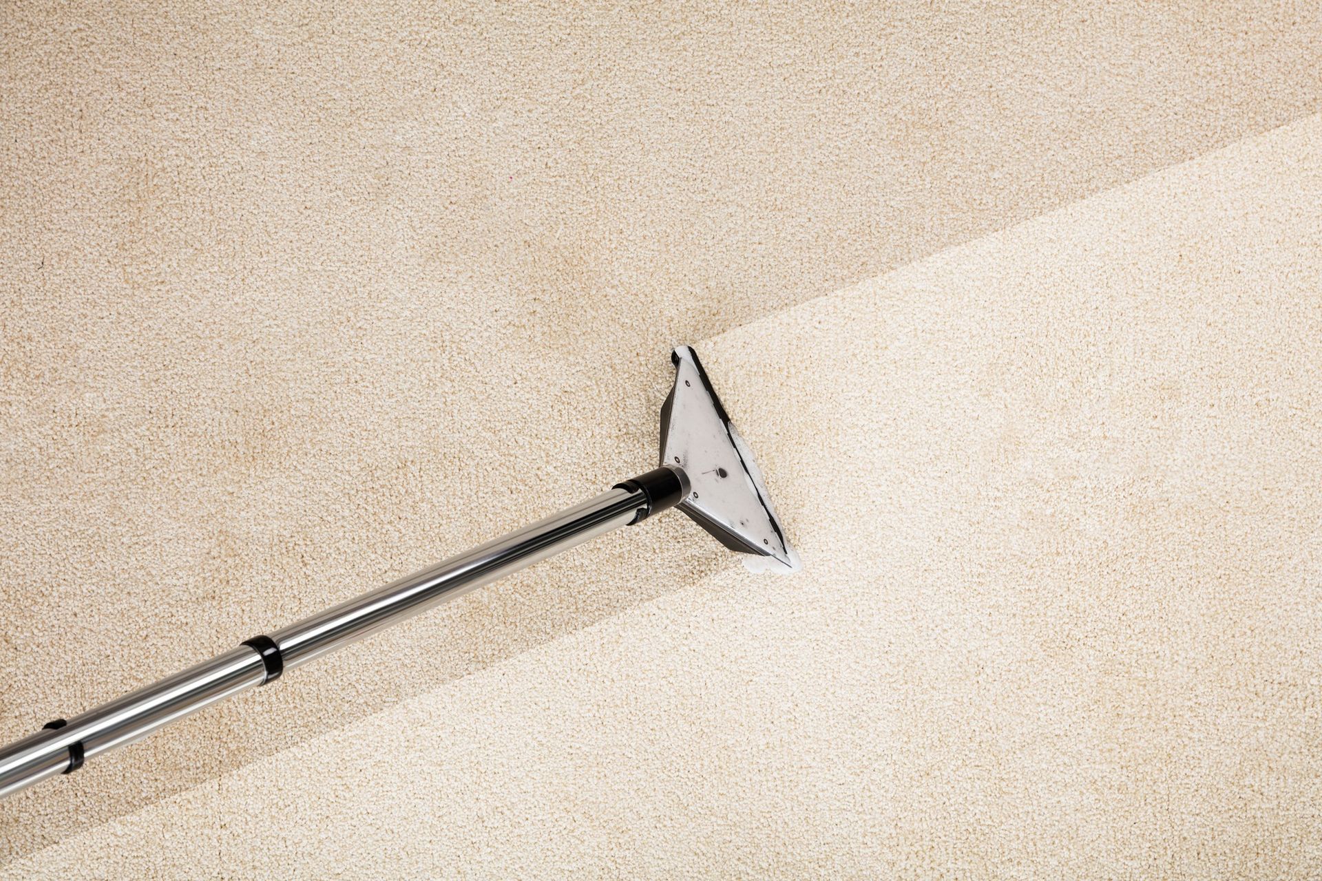 A vacuum cleaner is being used to clean a carpet.