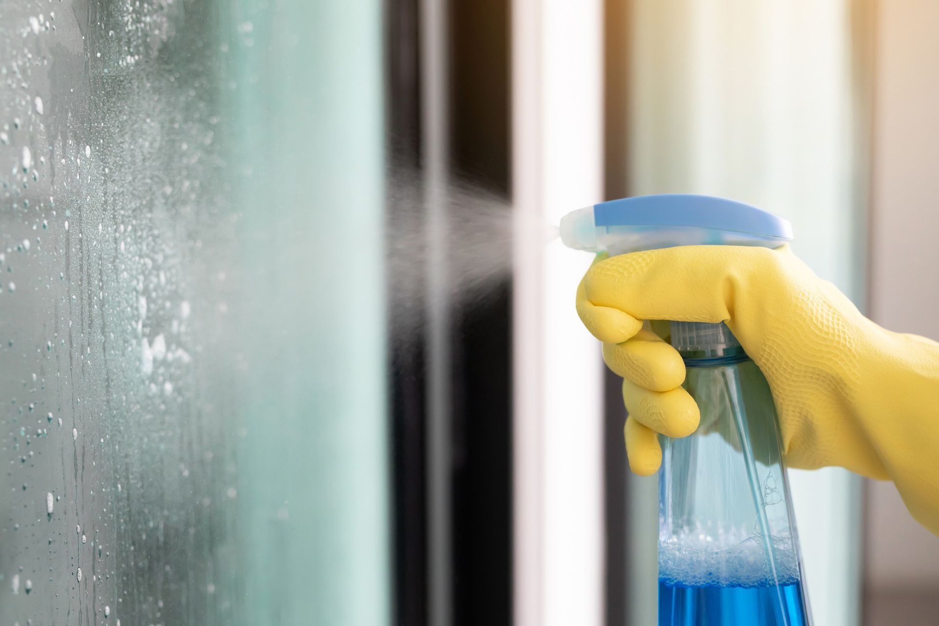 A person is cleaning a window with a spray bottle.
