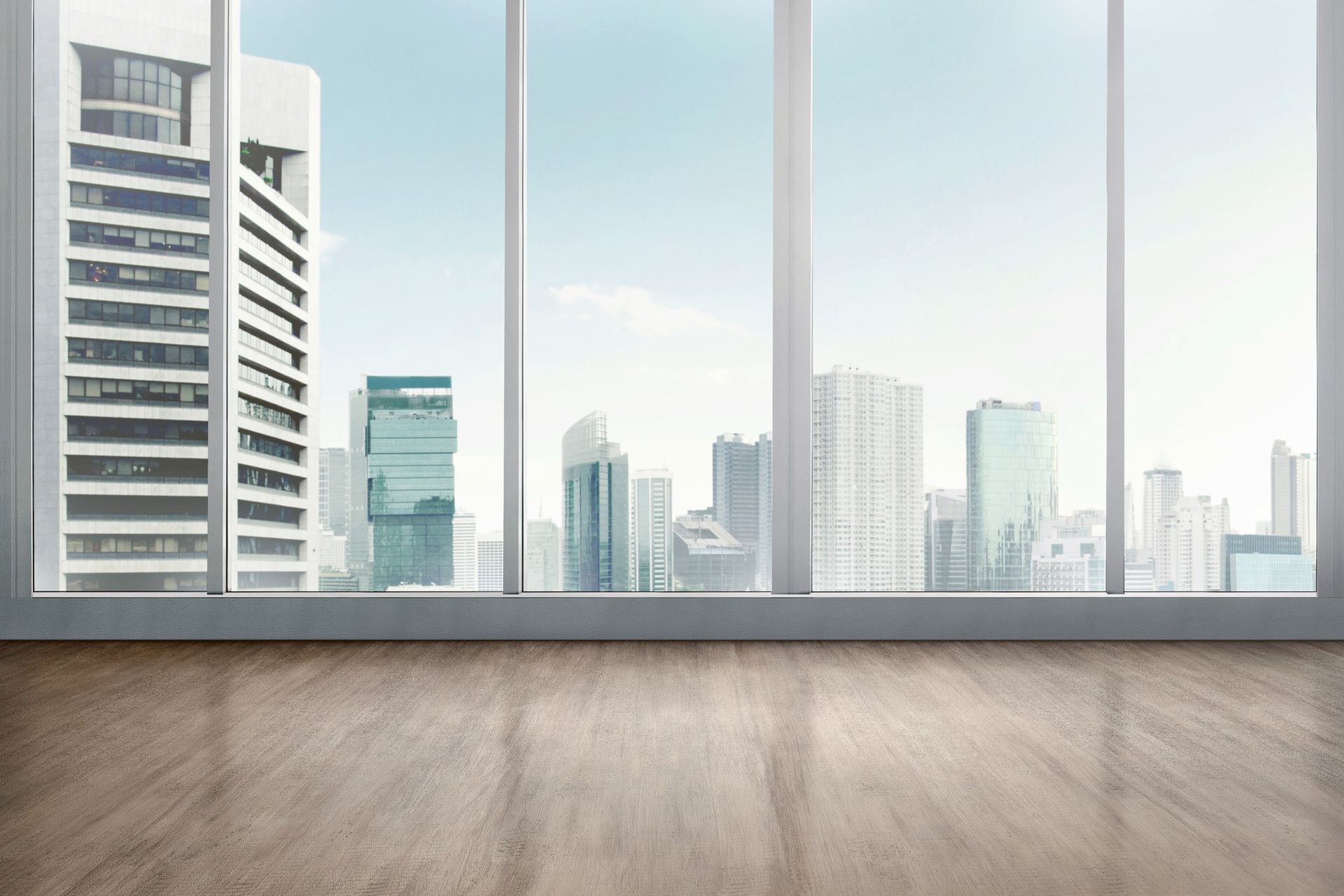 A room with a view of a city skyline through a large  clean window.