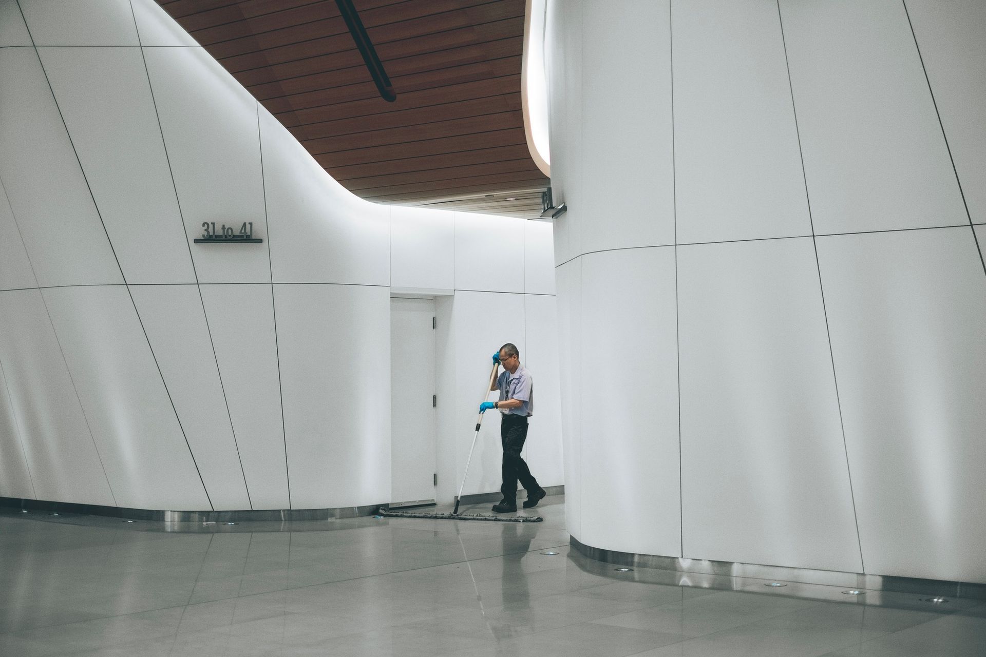A man is cleaning the floor of a building with a mop.