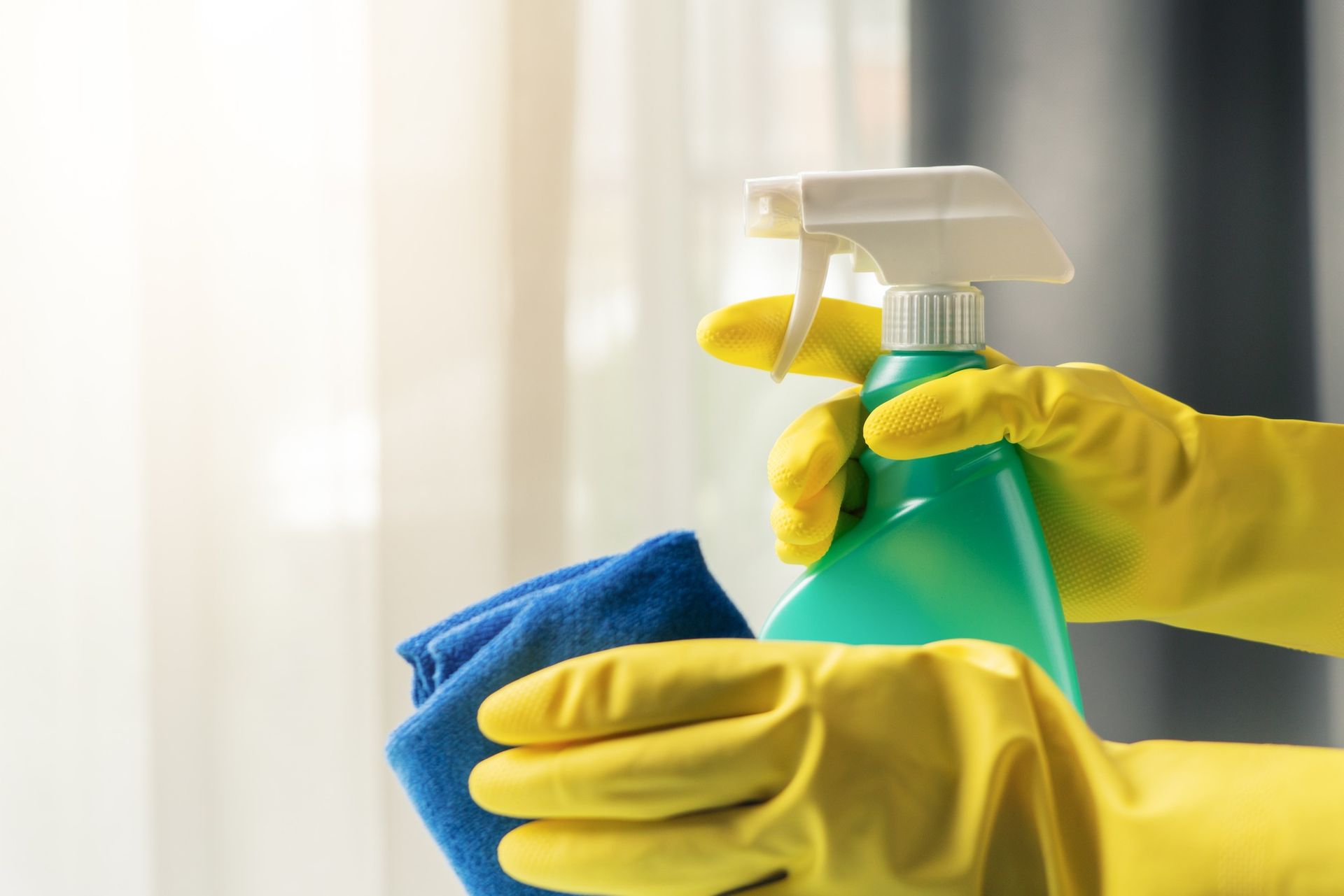 A person is cleaning a window with a spray bottle and a cloth.