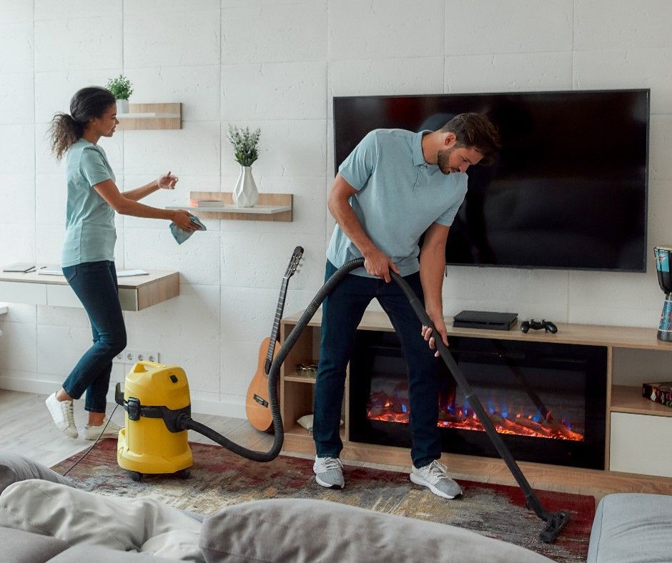 A man and a woman is cleaning a living room.