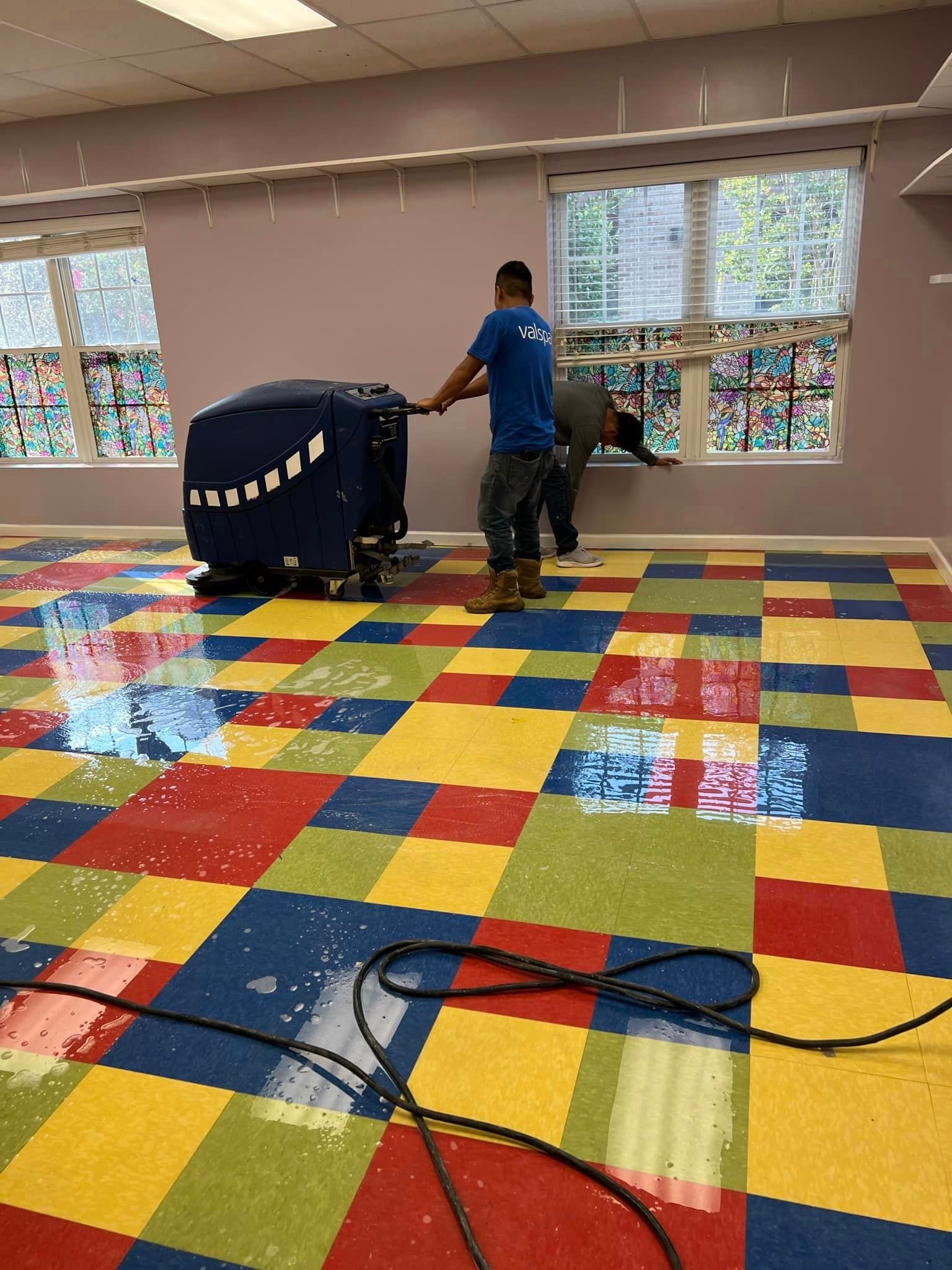 A man is cleaning a colorful carpet in a room.