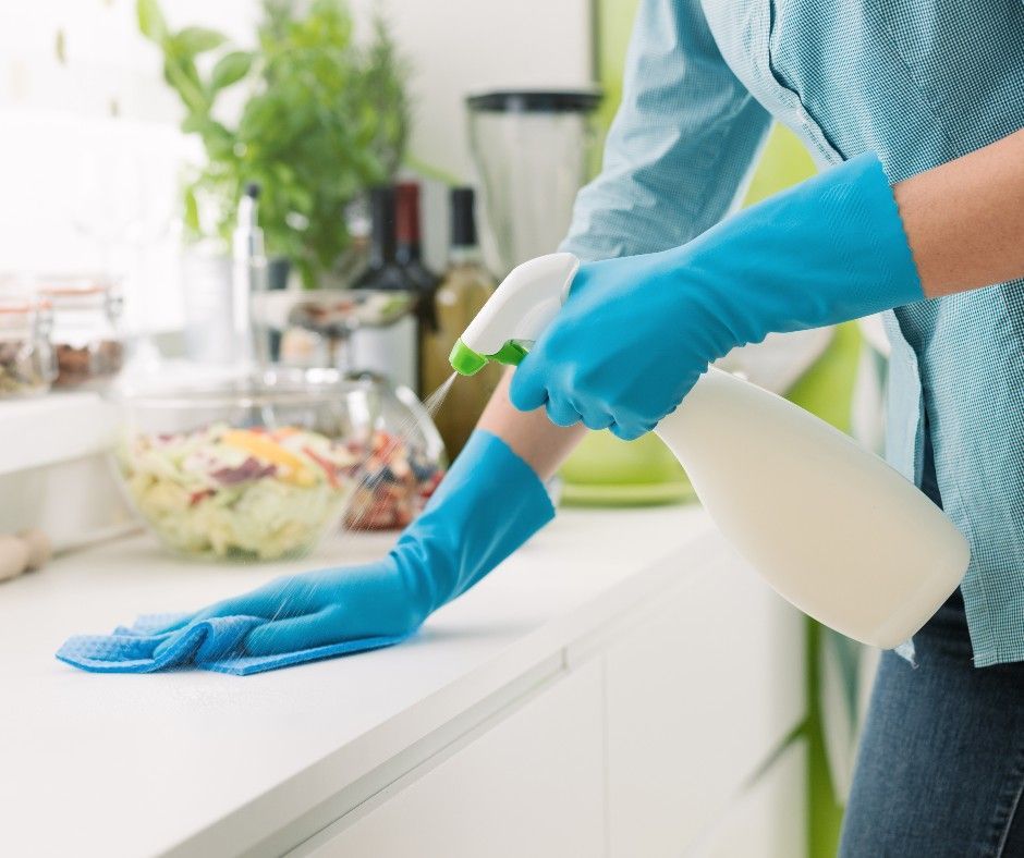 A person wearing blue gloves is cleaning with a spray bottle.