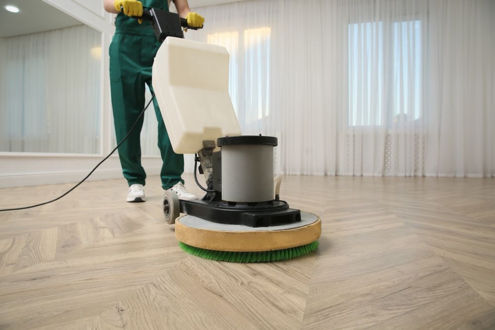 A man is cleaning a wooden floor with a machine.