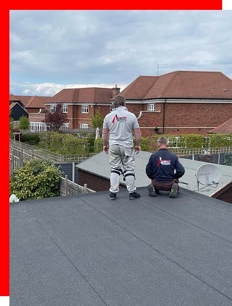 two men are working on a roof in front of a brick building .