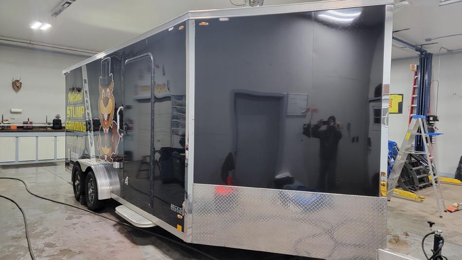 A black trailer is parked in a garage.