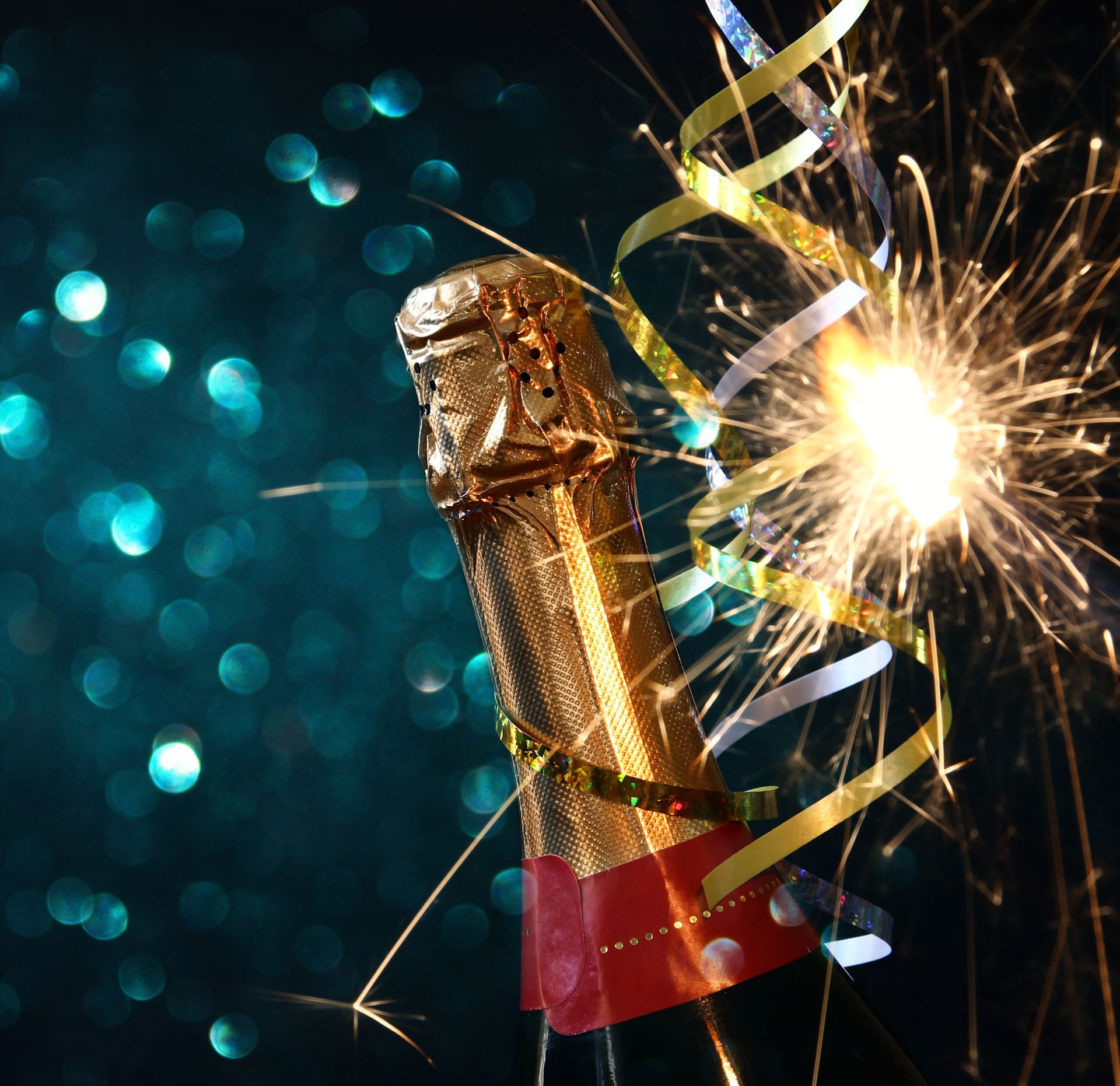 A bottle of champagne with sparklers and ribbons coming out of it