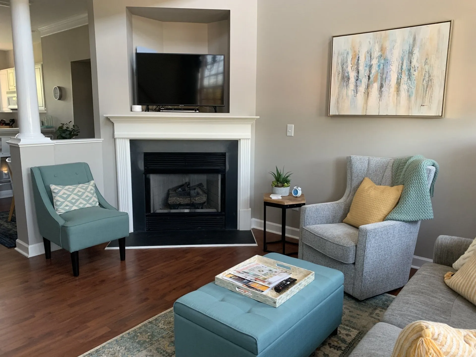 A living room with a fireplace , chairs , ottoman and television.