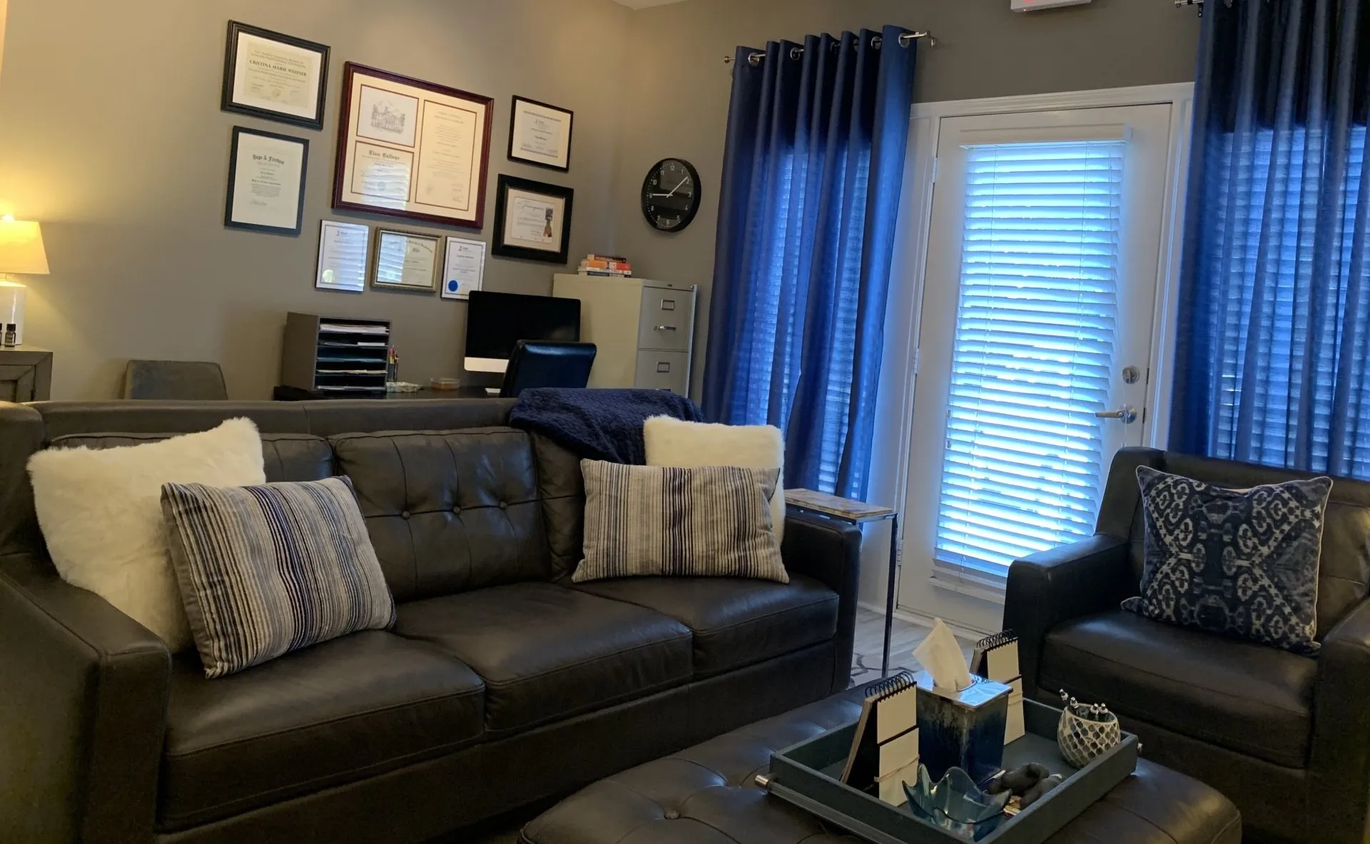 A living room with a couch , chair , coffee table and blue curtains.