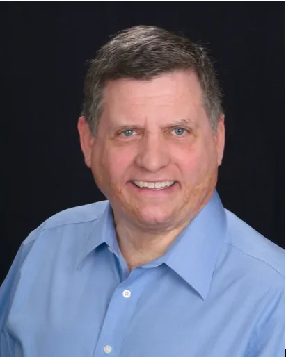 A man in a blue shirt is smiling for the camera