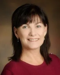 A woman in a red shirt is smiling for the camera.