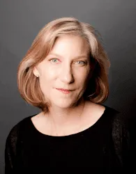 A woman with blonde hair is wearing a black shirt and looking at the camera.