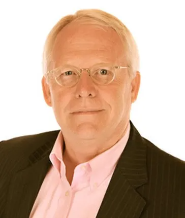 A man wearing glasses and a suit is looking at the camera