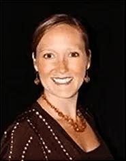 A woman wearing a necklace and earrings is smiling for the camera.