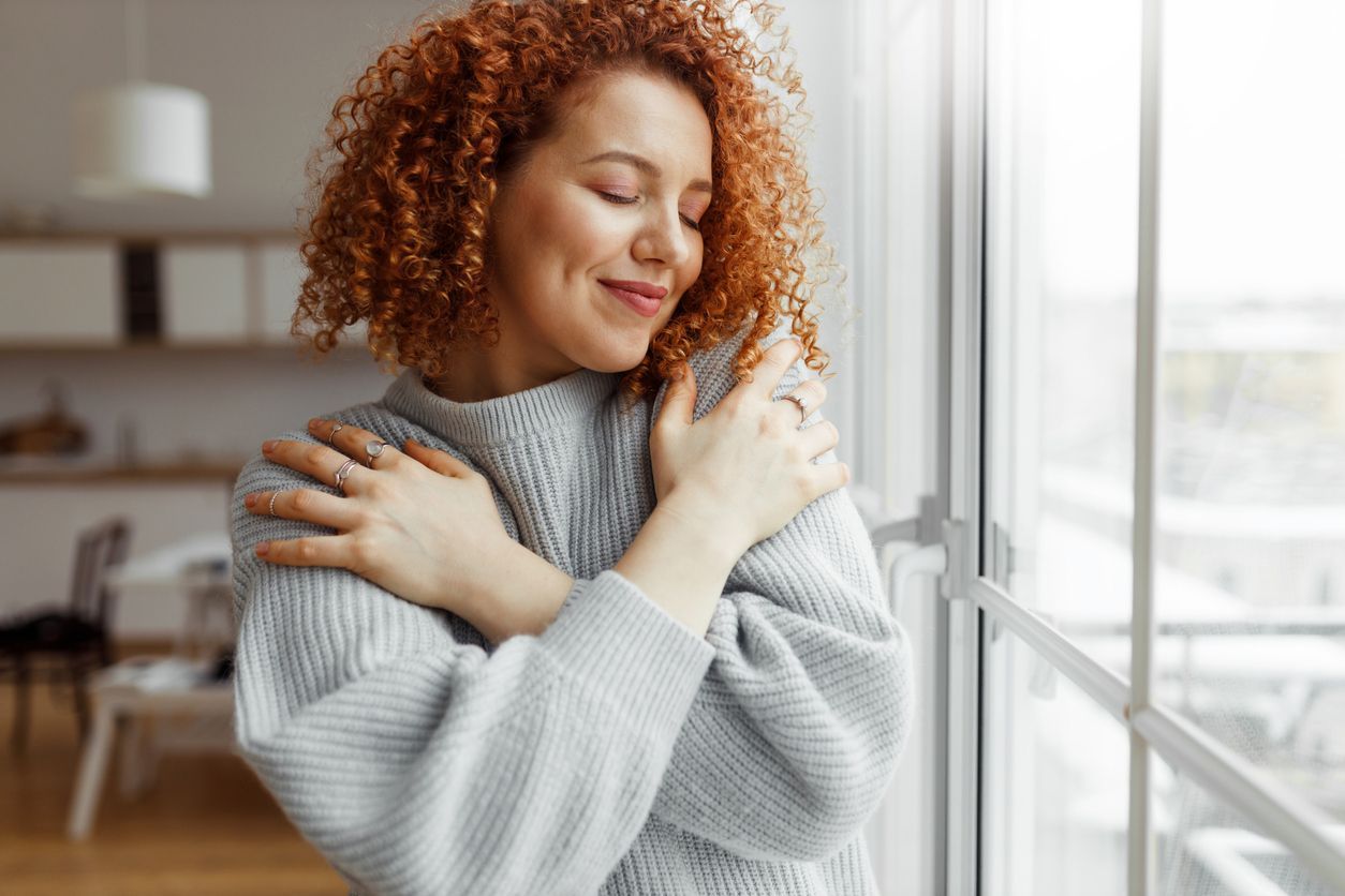 Curly red haired woman smiling with warm sweater