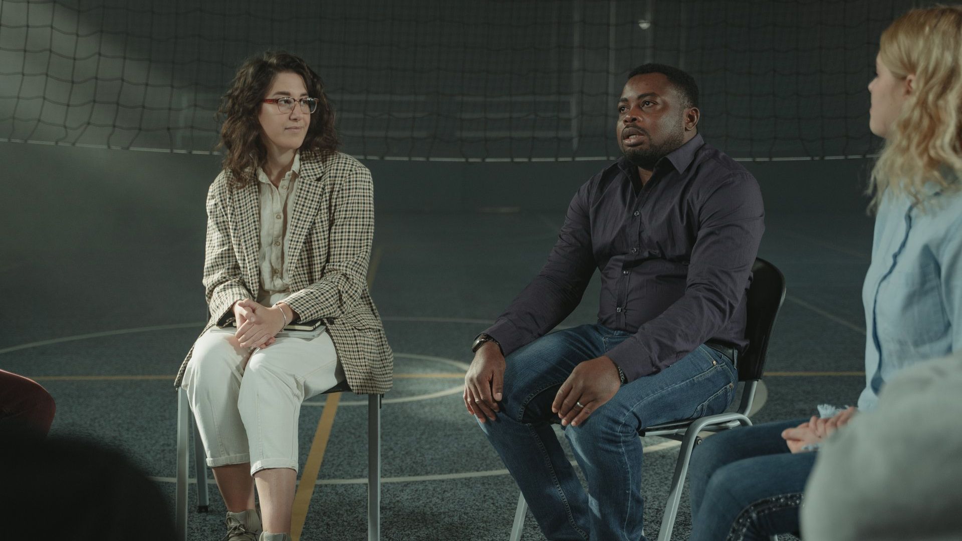A group of people are sitting in chairs in a circle having a conversation.