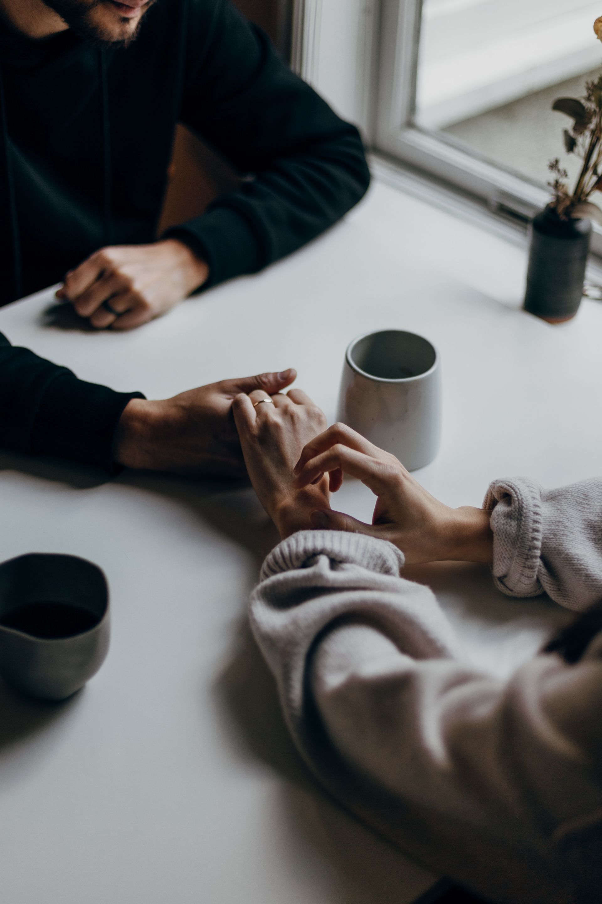 A man and a woman are sitting at a table holding hands.