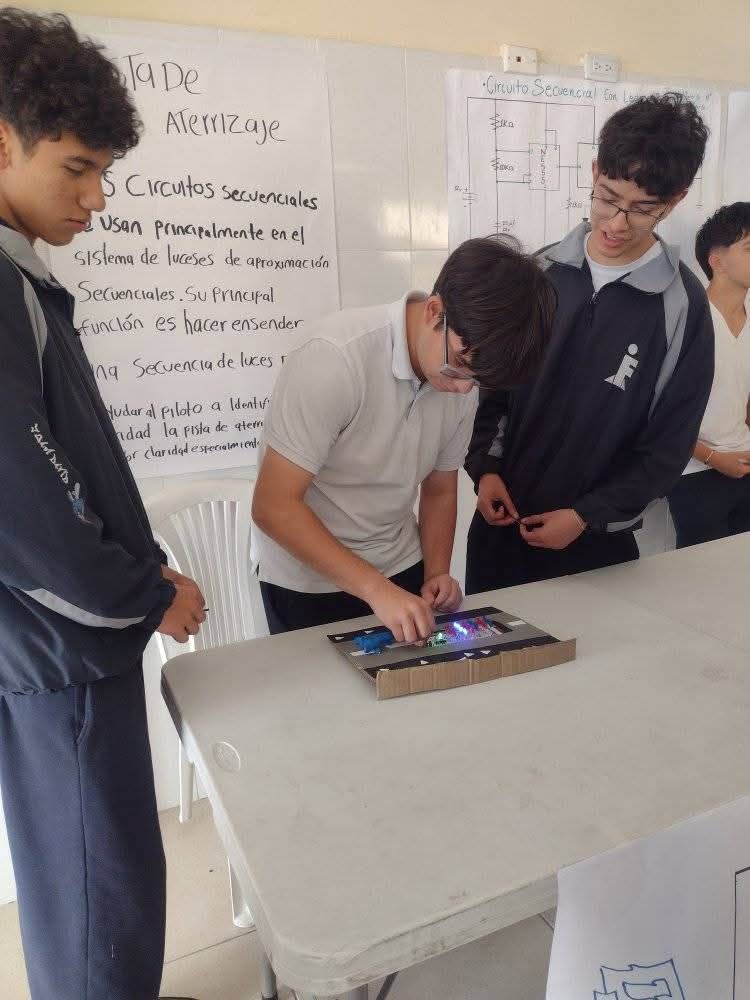 Estudiantes alrededor de una mesa usando una tableta en un taller de aula.