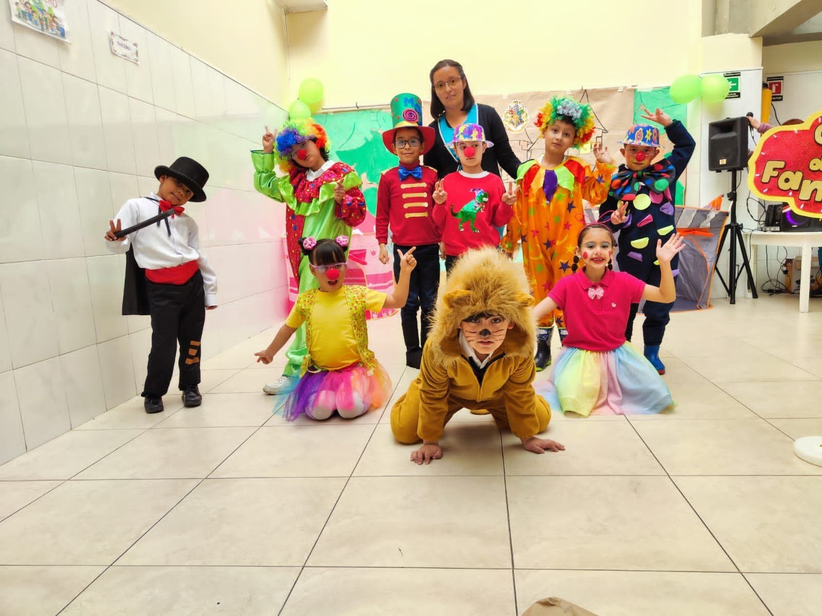 Niños con coloridos disfraces posando en un luminoso salón, con uno de ellos agachado con un disfraz de león en primer plano.