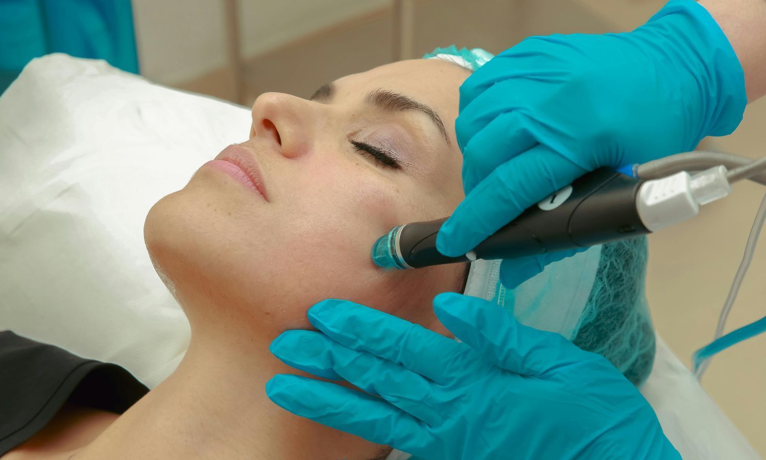 Woman receiving facial treatment; blue-gloved hands holding device to her face in a medical setting.