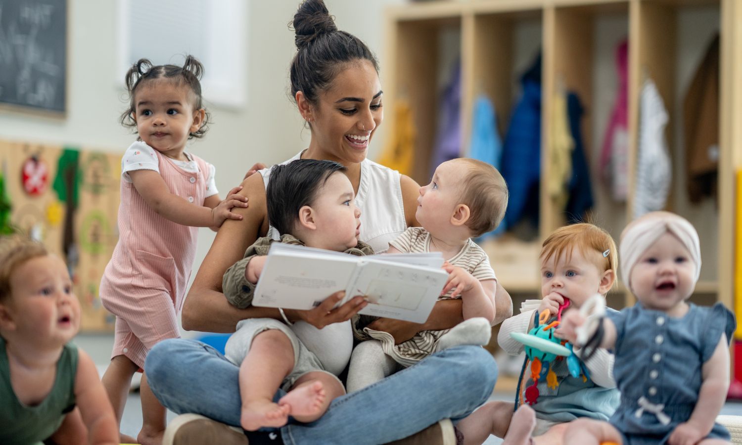 Teacher reading to a group of babies in a classroom.