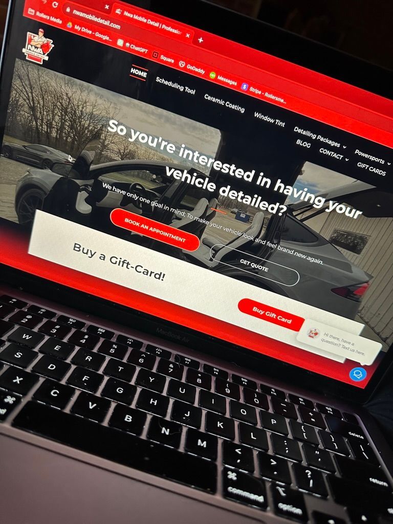 Laptop displaying a red and white website offering car detailing services.
