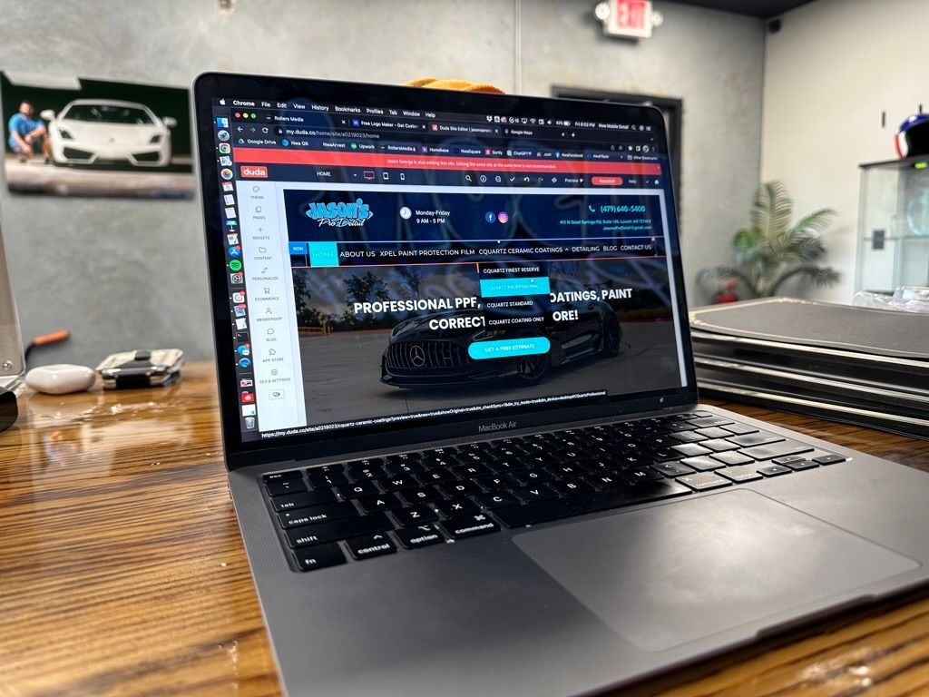 Laptop on a desk displaying a website, car in background.
