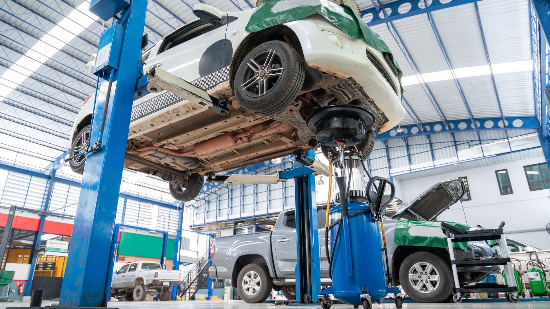 Car lifted in auto repair shop; vehicle maintenance underway.