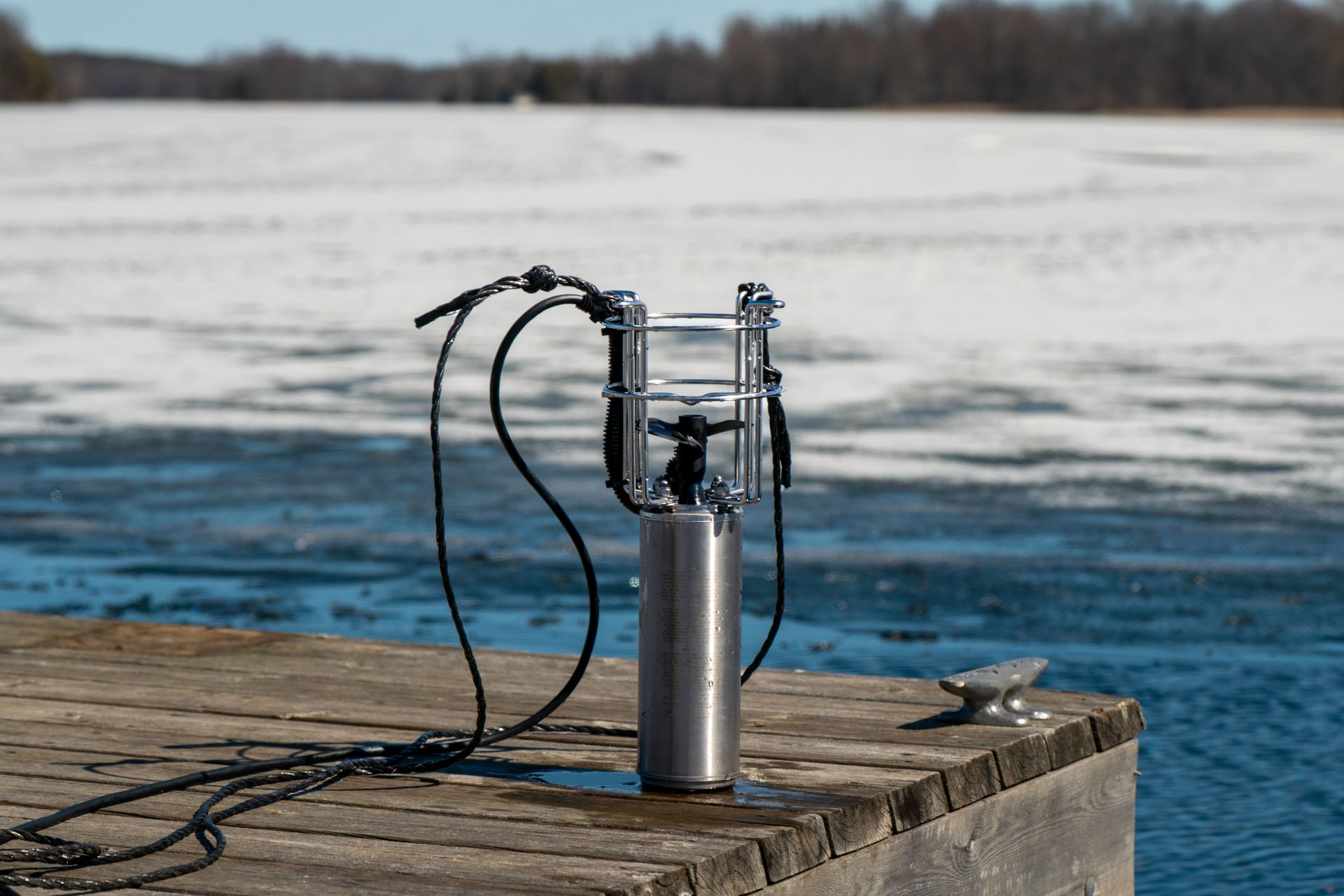 A device is sitting on a wooden dock next to a body of water.