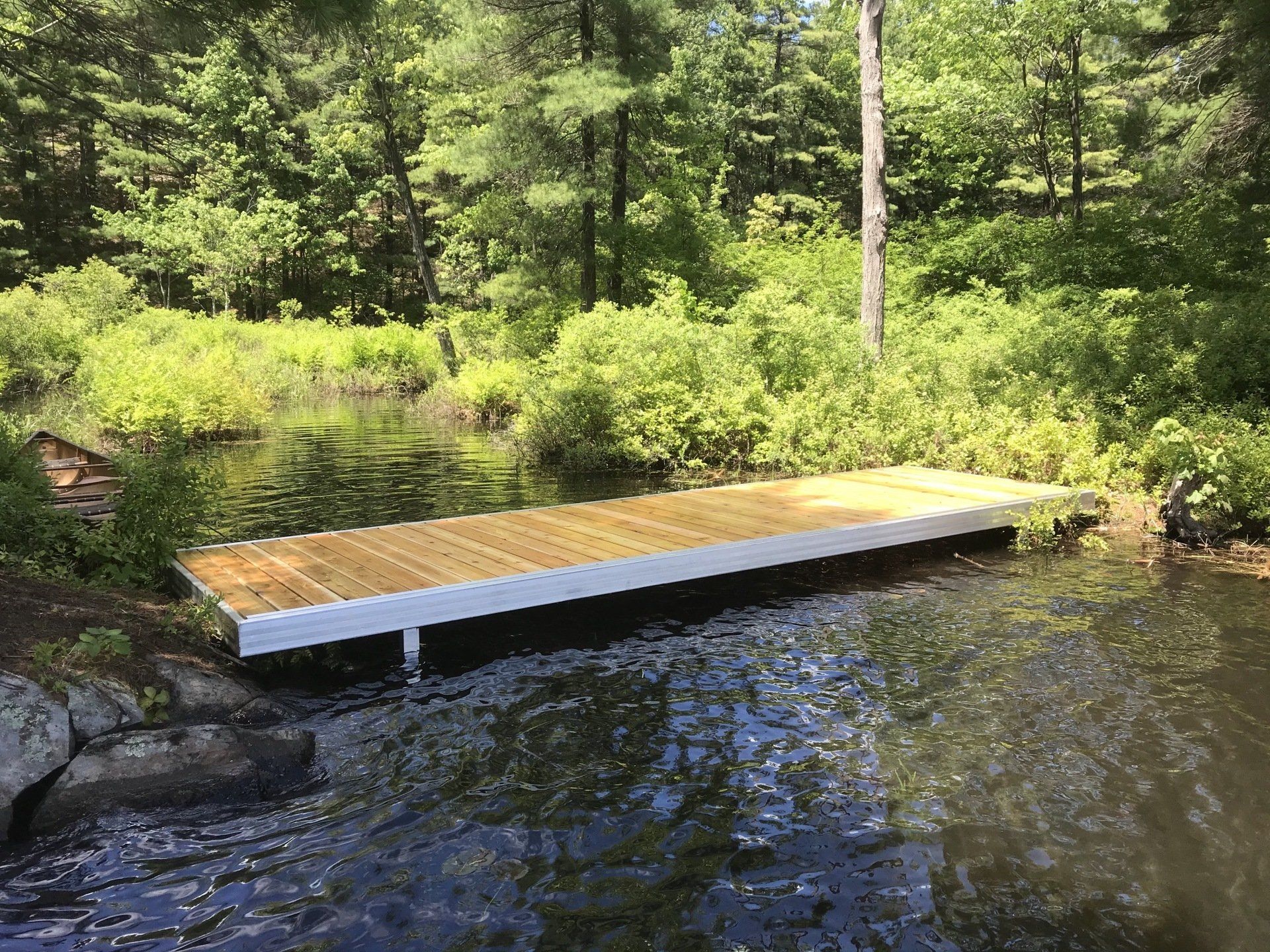 A wooden dock is in the middle of a lake surrounded by trees.